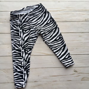 May include: Black and white zebra print leggings. The leggings are made of a stretchy fabric and have a comfortable fit.