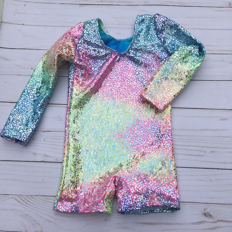 May include: A long-sleeved leotard with a rainbow iridescent pattern. The fabric has a textured, glittery finish.
