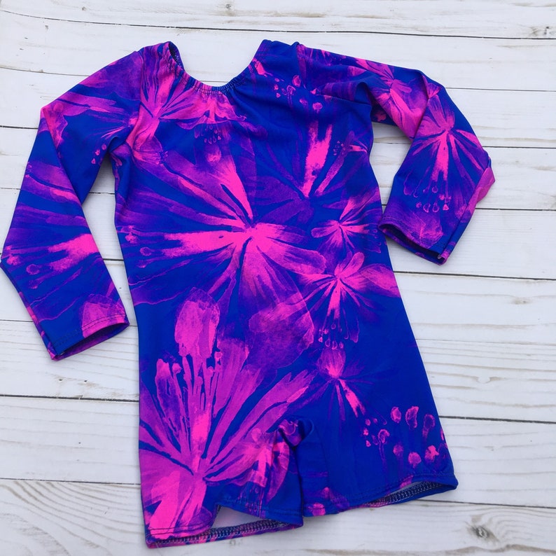 May include: A long-sleeved leotard with a blue background and a pink floral pattern. The leotard has a scoop neck and long sleeves.