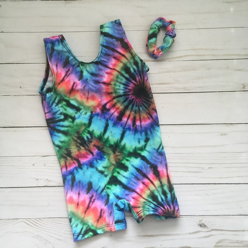 gymnastics or dance tank style biketard in a swirl pattern tie dye print of pink, hot pink, yellow, green, turquoise and purple. shown with matching scrunchie