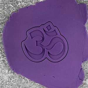 May include: Purple fondant with an Om symbol pressed into it.