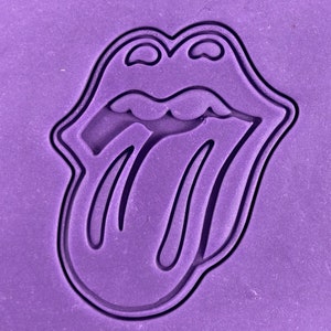 May include: Purple silicone mould of the Rolling Stones tongue logo. The mould is designed to create edible replicas of the iconic logo.