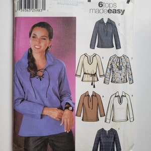 Può includere: Un cartamodello per sei top, con una modella che indossa uno dei top. Il cartamodello si chiama "Simplicity 6tops made easy" e include le istruzioni per realizzare una varietà di top, tra cui un top blu con scollo a lacci, un top marrone con scollo a V, un top bianco con scollo a V, un top floreale con scollo a balze, un top a quadri blu e bianco con scollo a V e un top blu con scollo a V.