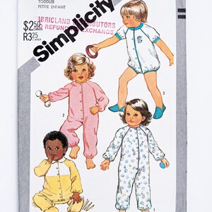 May include: Simplicity pattern for toddler clothing, showcasing four different styles of one-piece outfits. The outfits include a pink jumpsuit, a white romper with blue trim, a yellow and white jumpsuit, and a white jumpsuit with a floral pattern.