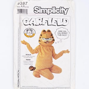 Può includere: Una busta per cartamodello Simplicity, numero 9387, per un costume di Garfield. La busta di carta bianca presenta il testo 'GARFIELD' e 'HOW CAN YOU RESIST THIS FACE?'. Mostra un costume da gatto arancione con cappuccio, coda e muffole.