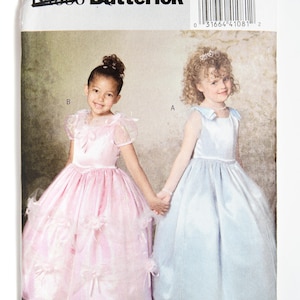 Op de afbeelding: Een naaipatroon voor twee meisjesjurken. Het patroon is voor een lichtblauwe jurk met een ronde hals en een roze jurk met een sweetheart-halslijn. Het patroon is van Butterick.