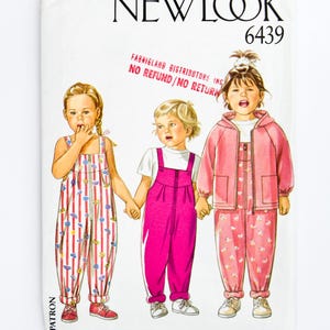 May include: A New Look sewing pattern showing three children's outfits. The designs include a striped jumpsuit, pink dungarees, and a pink hooded jacket and trousers set. The pattern number is 6439.