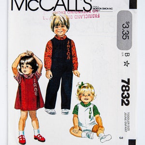 Puede incluir: Patrón de costura McCall's número 7832 para ropa de tamaño de niño pequeño. El patrón incluye tres atuendos: un vestido de cuadros rojos y blancos, un mono azul con una camisa estampada roja y blanca y un mono blanco con una camisa estampada verde y blanca. El patrón está a la venta por $ 3,35.