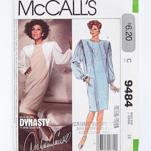 Könnte beinhalten: McCall's Schnittmuster Nummer 9484 für ein Kleid. Das Schnittmuster ist für eine Größe für Mädchen 16. Das Schnittmuster ist für ein Kleid mit langen Ärmeln und einem runden Ausschnitt. Das Kleid ist in hellblau mit einem karierten Muster dargestellt. Das Schnittmuster kostet 6,20 $.