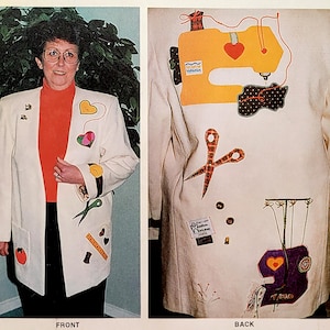 May include: A white blazer decorated with colorful sewing-themed appliques, including a sewing machine, scissors, buttons, and thread. The blazer has a red turtleneck underneath and is worn by a person with glasses. The back of the blazer features a sewing machine applique with a red heart and a pair of scissors.