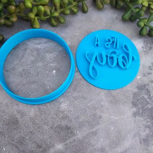May include: A blue plastic cookie cutter with a round shape and a separate imprint that reads "A little good".