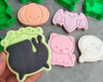 May include: A set of Halloween-themed cookie cutters, including a pumpkin, a bat, a ghost, a cauldron, a cat, and a witch's hat. The cutters are made of green plastic and are in various shapes and sizes.