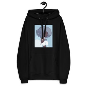 May include: Black hoodie with a graphic of a woman with a large afro and a white dress. The background is a light blue color.