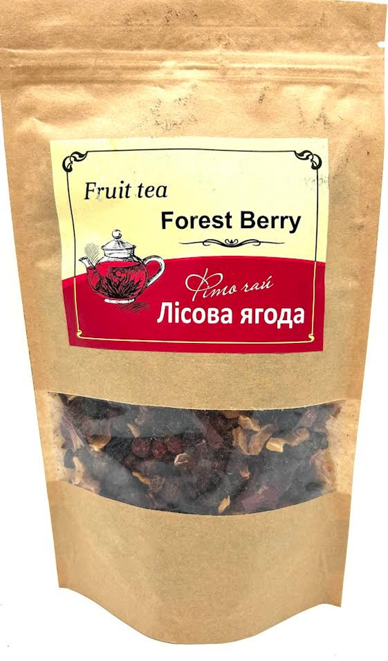 Pu&ograve; includere: Un sacchetto di carta marrone di t&egrave; alla frutta con una finestra trasparente che mostra le foglie di t&egrave;. L'etichetta recita "Fruit tea Forest Berry" con uno sfondo rosso e un'illustrazione di teiera.