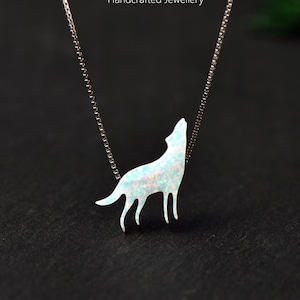 May include: A silver necklace featuring a howling wolf pendant. The pendant is white with a shimmering, opalescent effect. The necklace is displayed against a dark background, with the text "MICHELLELEE STUDIO Handcrafted Jewellery".