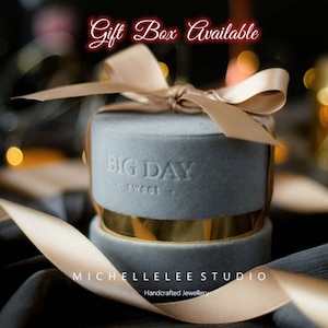 K&ouml;nnte beinhalten: Eine graue Samt-Schmuckschatulle mit einem goldenen Band und passendem Band. Auf der Schatulle steht "BIG DAY sweet". Der Text "Gift Box Available" steht oben. Der Text "MICHELLELEE STUDIO Handcrafted Jewellery" steht unten.