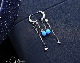 May include: A pair of silver earrings with a crescent moon design and dangling blue opal stones. Each earring has three small star charms hanging from the chain.