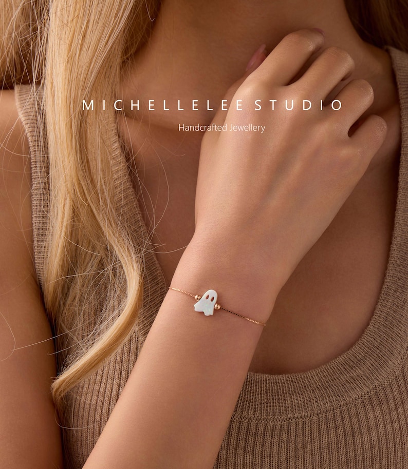 Pu&ograve; includere: Un delicato bracciale a catena in oro rosa con un piccolo ciondolo bianco a forma di fantasma. Il testo MICHELLELEE STUDIO Handcrafted Jewellery &egrave; visibile nella parte superiore dell'immagine. Il bracciale ha una catena sottile e regolabile.