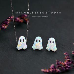 Pu&ograve; includere: Una collana e un paio di orecchini a lobo con pendenti a forma di fantasma in opale bianco con macchie iridescenti. La collana include una sottile catenina d'argento. Il testo MICHELLELEE STUDIO Handcrafted Jewellery &egrave; visibile in alto.