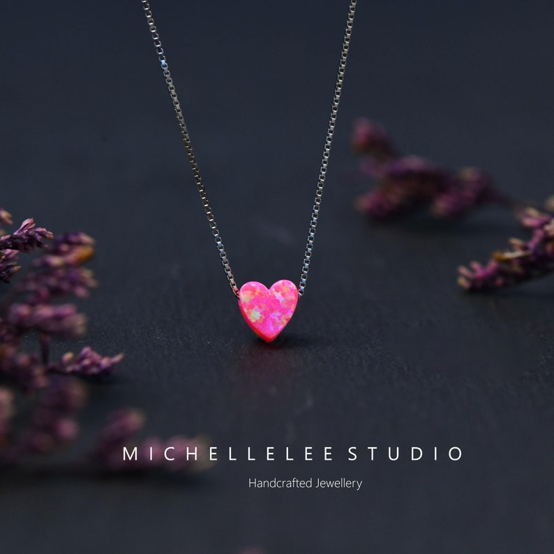 May include: A silver necklace featuring a pink heart-shaped pendant. The pendant has a textured finish and hangs from a fine chain. The image includes the text "MICHELLELEE STUDIO" and "Handcrafted Jewellery".