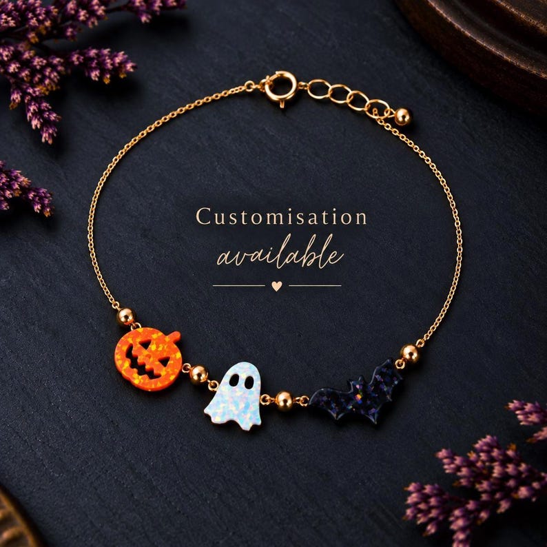 Pu&ograve; includere: Un bracciale a catena color oro con tre ciondoli: una zucca arancione glitterata, un fantasma bianco glitterato e un pipistrello viola scuro glitterato. Piccole perline color oro si trovano tra i ciondoli. Il testo Customisation available &egrave; presente.