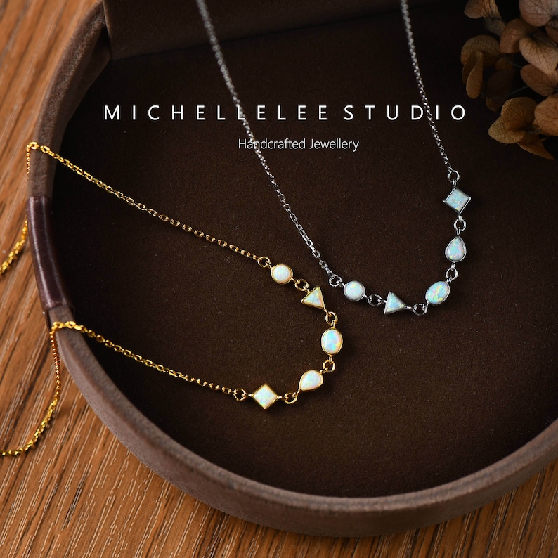 May include: Two delicate necklaces with opal stones in geometric shapes. The necklaces are on a brown background with the text "MICHELLE LEE STUDIO Handcrafted Jewellery".