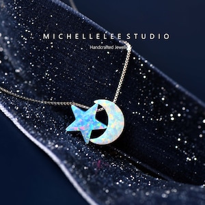 May include: A silver chain necklace with a crescent moon and star pendant made of iridescent opal. The pendant is on a black velvet background.  Handcrafted Jewellery by Michelle Lee Studio.