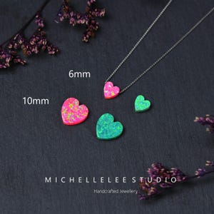 K&ouml;nnte beinhalten: Eine Sammlung von herzf&ouml;rmigem Opalschmuck. Das Bild zeigt eine Halskette mit einem 6-mm-Anh&auml;nger in Herzform in Rosa und lose 10-mm-Herzen in Rosa und Gr&uuml;n. Der Schmuck ist handgefertigt. Der Text "MICHELLELEE STUDIO" und "Handcrafted Jewellery" sind sichtbar.