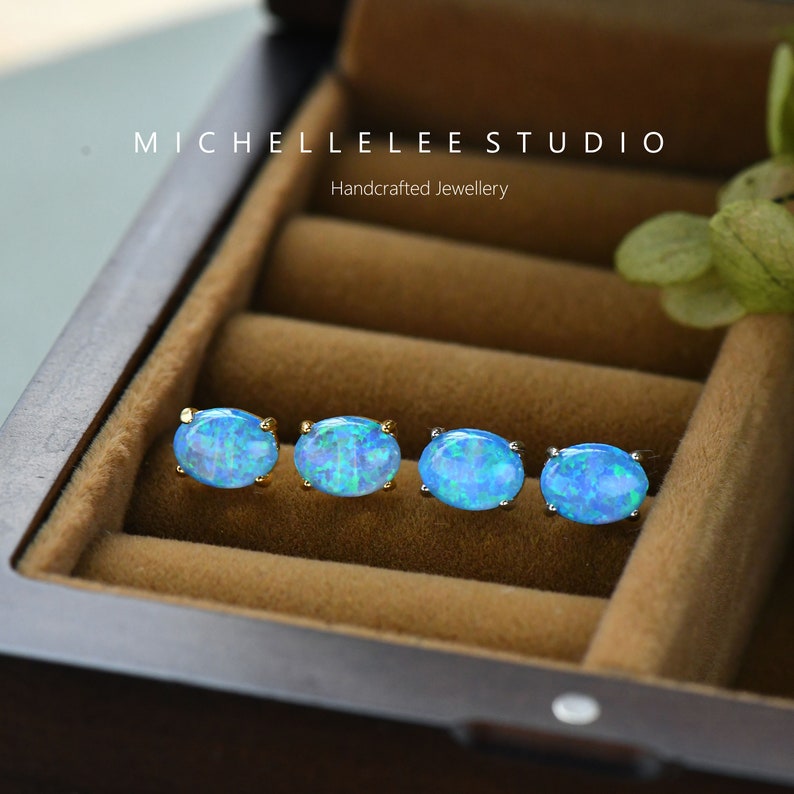 May include: Four pairs of oval-shaped blue opal earrings in a jewelry box. The earrings are set in gold and have a delicate design. The box is made of wood and has a velvet lining.