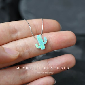 Könnte beinhalten: Eine silberne Kettenkette mit einem hellblauen Opal-Kaktus-Anhänger. Der Anhänger ist ein schlichtes, minimalistisches Design. Die Kette ist handgefertigt.