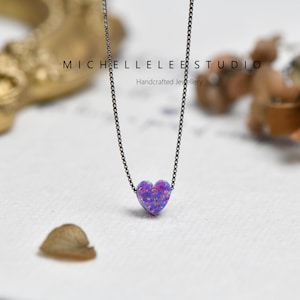 May include: A necklace with a heart-shaped pendant in shades of purple and blue, suspended from a fine, dark chain. The image includes the text "MICHELLELEE STUDIO Handcrafted Jewellery".