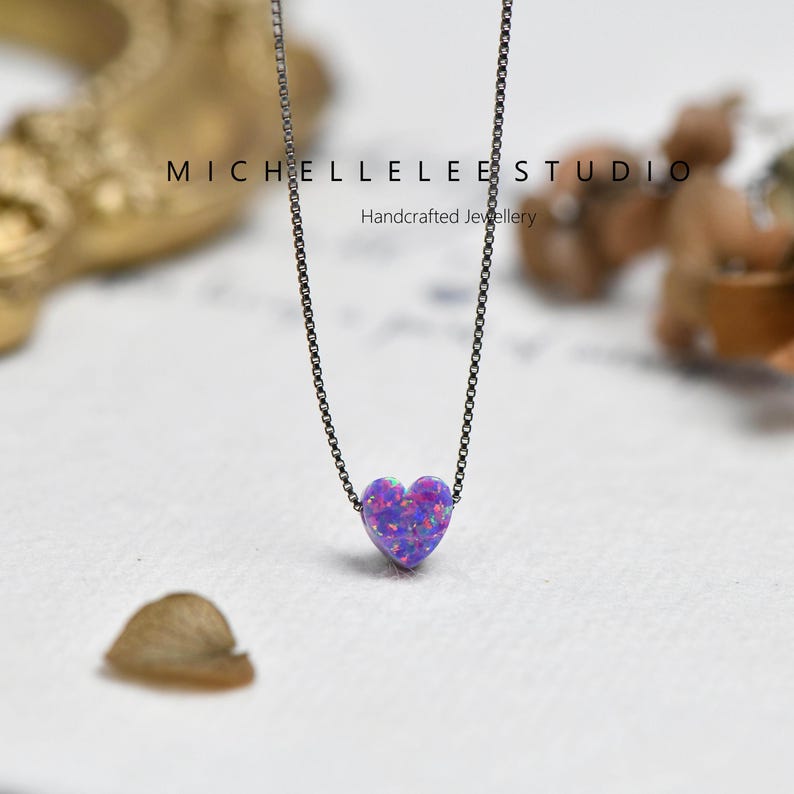 May include: A necklace with a heart-shaped pendant in shades of purple and blue, suspended from a fine, dark chain. The image includes the text "MICHELLELEE STUDIO Handcrafted Jewellery".