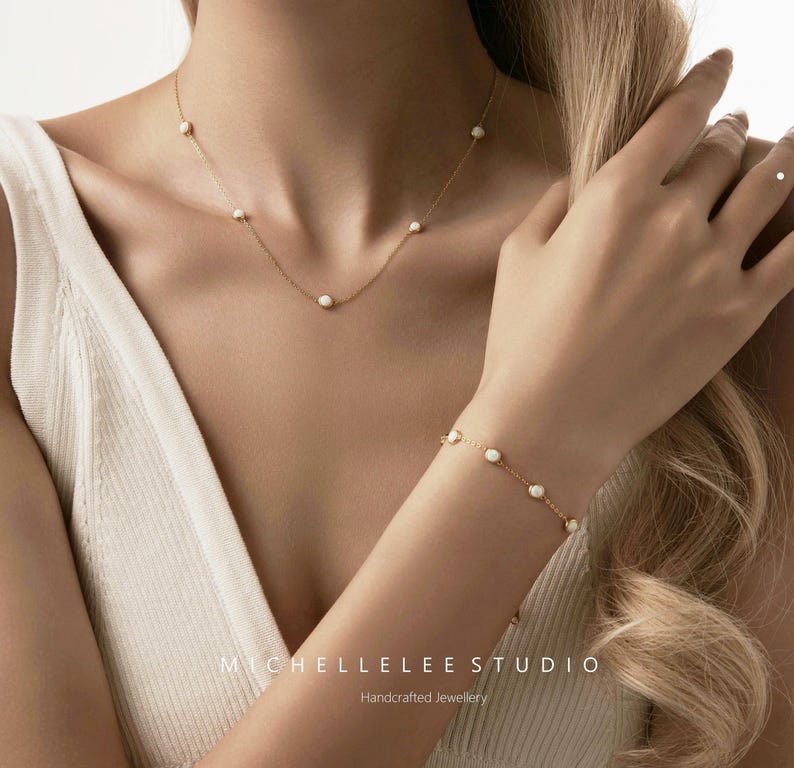 Pode incluir: Um conjunto de colar e pulseira dourados com pequenas pedras brancas redondas. As joias t&ecirc;m um design minimalista e delicado. A imagem tamb&eacute;m inclui o texto "MICHELLELEELEE STUDIO Handcrafted Jewellery".