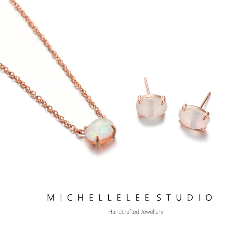 May include: A delicate rose gold necklace and matching earrings with oval-shaped white opal stones. The jewelry is handcrafted and features a simple chain design.