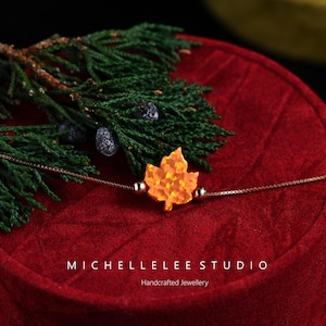 Pulsera de ópalo con forma de hoja de arce naranja y cadena de plata de ley.