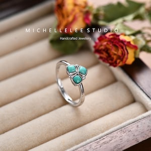 May include: A silver ring with a turquoise stone design. The ring is set in a wooden ring box.