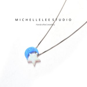 May include: A silver chain necklace with a blue crescent moon and a white star pendant. The pendant is made of opal.