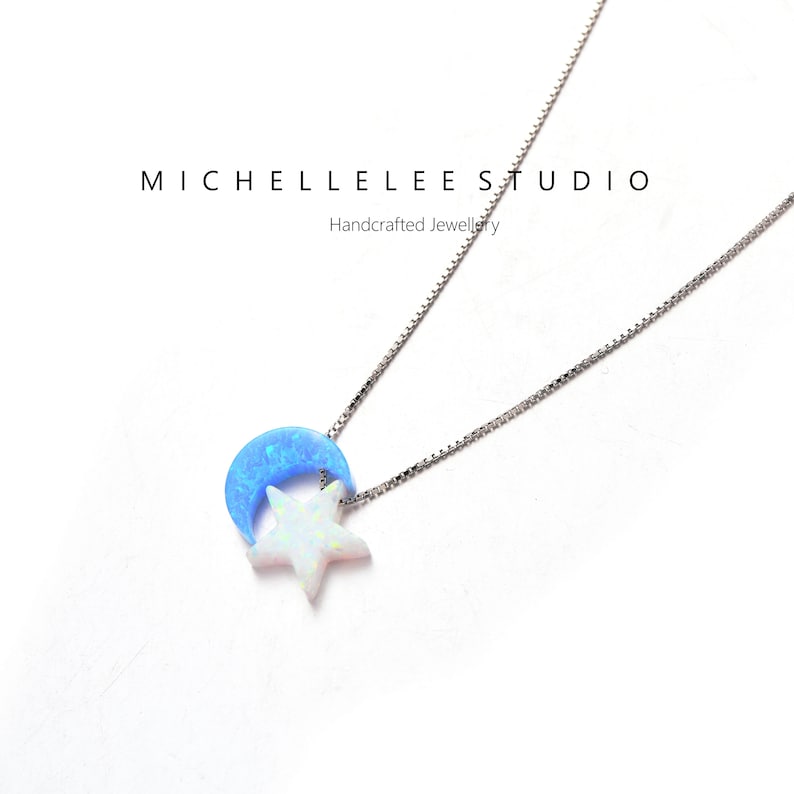 May include: A silver chain necklace with a blue crescent moon and a white star pendant. The pendant is made of opal.