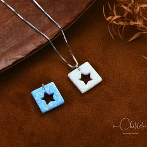 May include: A silver chain necklace with two opal pendants. The pendants are square shaped with a star cut out. One pendant is white opal and the other is blue opal.