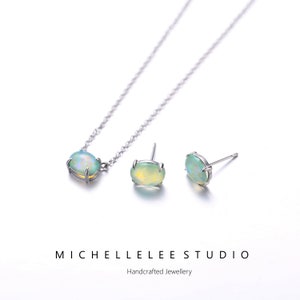May include: A silver necklace and earrings set with a green opal gemstone. The necklace has a delicate chain and the earrings are stud style. The set is handcrafted and comes from Michelle Lee Studio.
