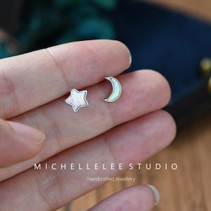 May include: A pair of silver earrings with opal stones. One earring is a crescent moon and the other is a star.