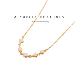 May include: A gold chain necklace with a delicate design featuring five white opal stones in different shapes, including a square, a teardrop, a circle, a triangle, and an oval. The necklace is on a white background.  MICHELLE LEE STUDIO Handcrafted Jewellery