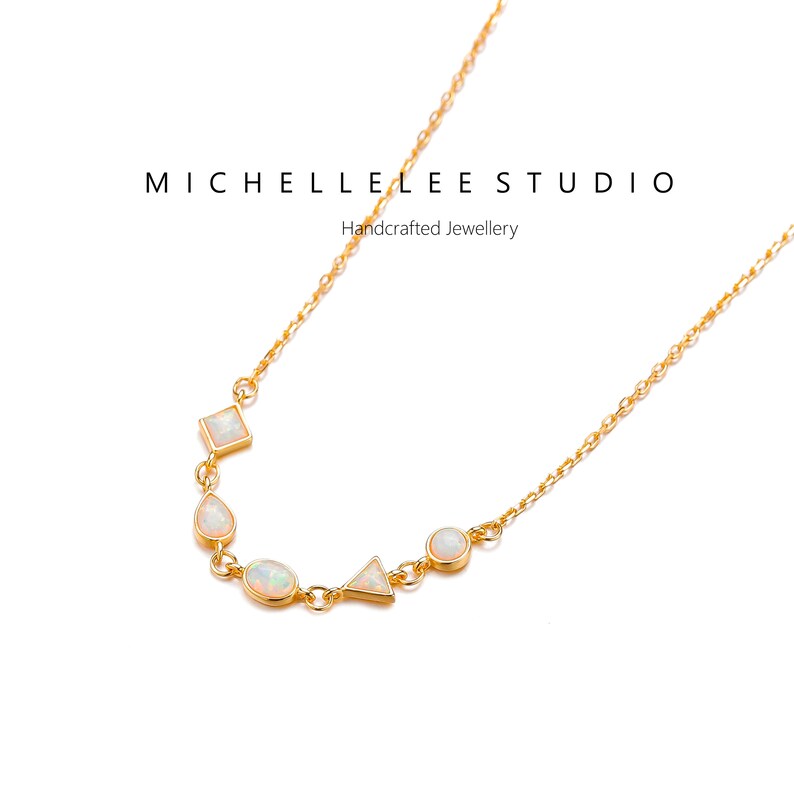 May include: A gold chain necklace with a delicate design featuring five white opal stones in different shapes, including a square, a teardrop, a circle, a triangle, and an oval. The necklace is on a white background.  MICHELLE LEE STUDIO Handcrafted Jewellery