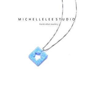 May include: A silver chain necklace with a light blue square pendant featuring a star cutout. The pendant is made of opal.