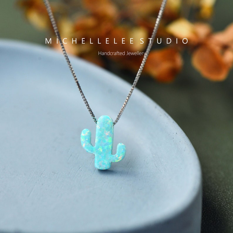 Op de afbeelding: Een zilveren ketting met een blauwe opaal cactus hanger. De hanger is een eenvoudig, minimalistisch ontwerp in lichtblauwe kleur.
