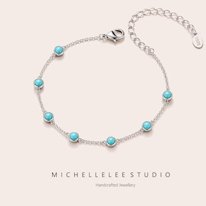 May include: A silver chain bracelet featuring six evenly spaced round turquoise-colored stones in bezel settings. The bracelet includes a lobster claw clasp and an adjustable extender chain with a small oval tag stamped with S925.