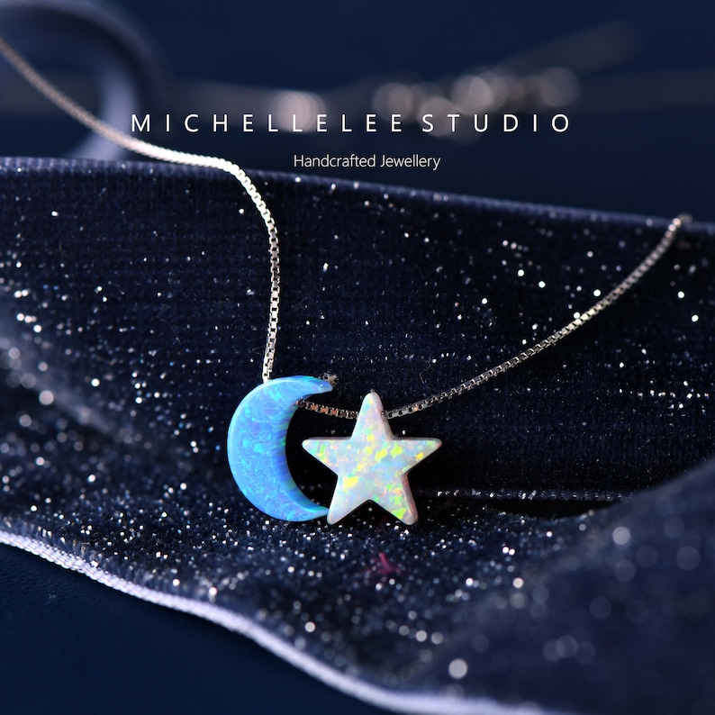 May include: A silver chain necklace with a blue opal crescent moon and a white opal star pendant. The necklace is on a dark blue velvet background.  Handcrafted Jewellery.