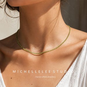 May include: A delicate, light green beaded necklace. The necklace is worn around the neck. The image also includes the text "MICHELLELEE STUDIO" and "Handcrafted Jewellery".