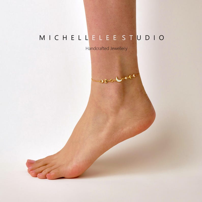 Peut inclure: Chevill&egrave;re dor&eacute;e avec une cha&icirc;ne d&eacute;licate et des breloques en forme de lune. La chevill&egrave;re est port&eacute;e &agrave; la cheville d'une personne. Le texte "MICHELLE LEE STUDIO Bijoux artisanaux" est visible en arri&egrave;re-plan.