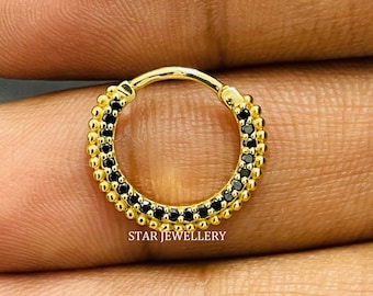 Pode incluir: Anel de nariz de ouro com pedras de zircônia cúbica pretas. O anel é feito de aço cirúrgico e está disponível em uma variedade de tamanhos.
